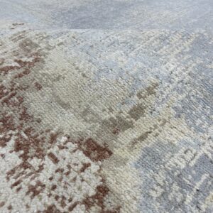 Close-up of a textured, abstract rug featuring chunky piles in rust, cream, gray, and beige colors.