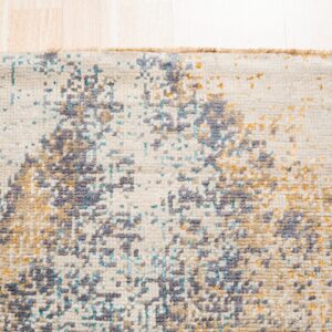 Close-up of a low-pile rug with abstract splotches of gray, blue, and gold on a cream background.