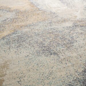 Low-pile rug with abstract distressed patterns in cream, gray, gold, and teal on light wood floors.