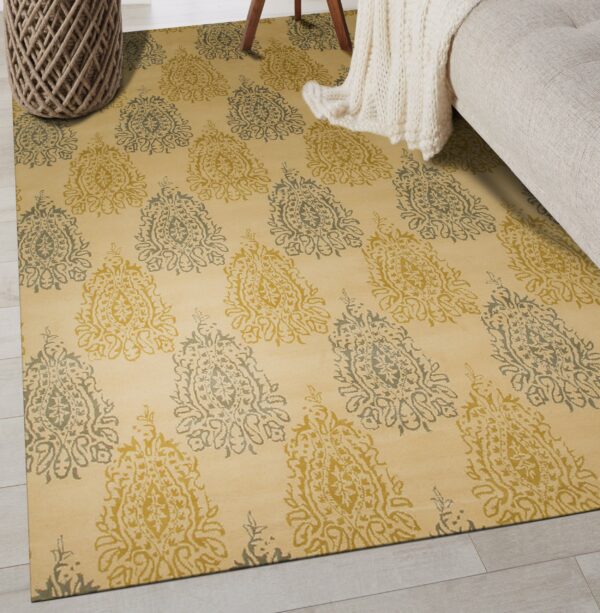 Yellow rug with alternating gold and sage medallion motifs sits next to a cream knit blanket.