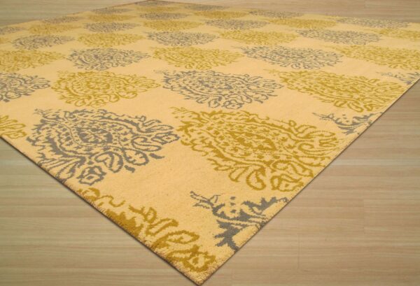 Yellow rug with alternating gray and olive medallions rests on light wood plank flooring.