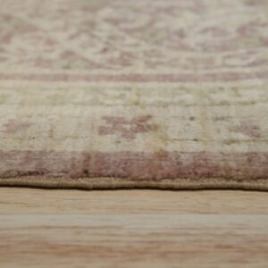Low-angle view showing the edge of a beige and pink patterned rug on wood flooring.