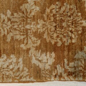 High pile rug in shades of caramel and beige with a distressed floral pattern on a light wood plank floor.