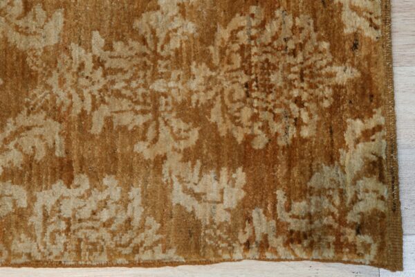 High pile rug in shades of caramel and beige with a distressed floral pattern on a light wood plank floor.