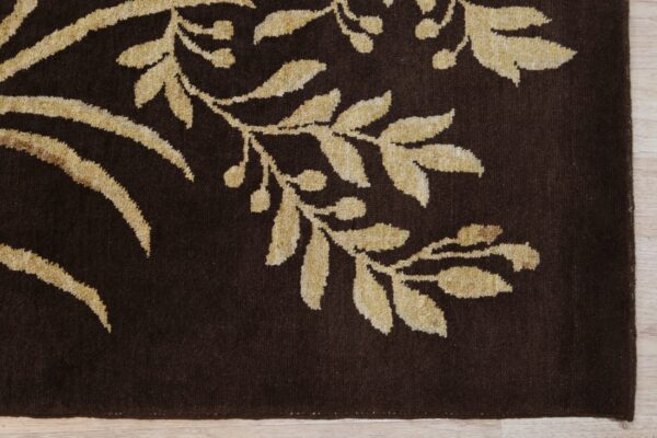 Dark brown rug featuring a raised tan floral pattern rests on light-colored wood planks.