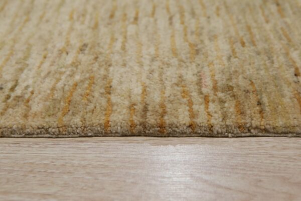 High-pile beige rug with irregular yellow striping rests on light wood plank flooring.