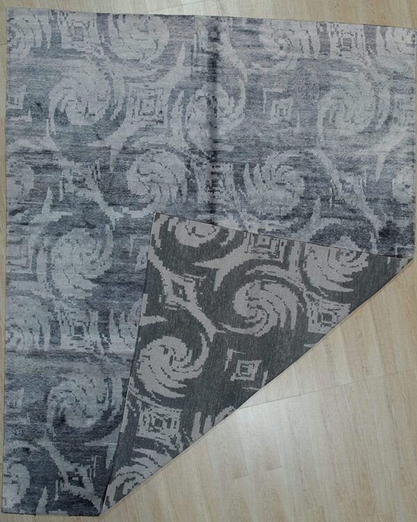 Abstract gray rug with swirling, low pile pattern displayed on light wood flooring.