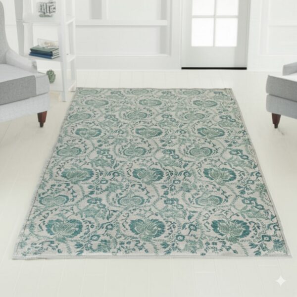 Ornate light teal floral rug over white plank flooring, flanked by gray upholstered chairs.