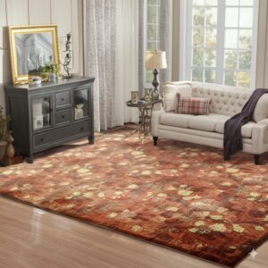 A deep red and gold floral area rug sits on a shiny wood floor in a sunlit living space.
