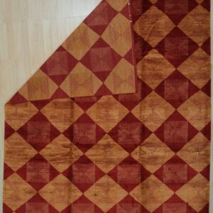 Geometric rug with alternating burgundy and textured gold diamonds displayed on light plank flooring.