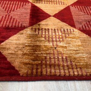Close-up of a medium-pile rug featuring large red and gold geometric patterns on light wood flooring.