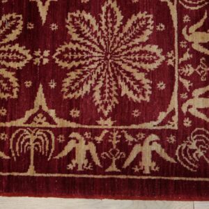 Burgundy textured rug with a tan repeating floral and stylized bird pattern on light wood flooring.
