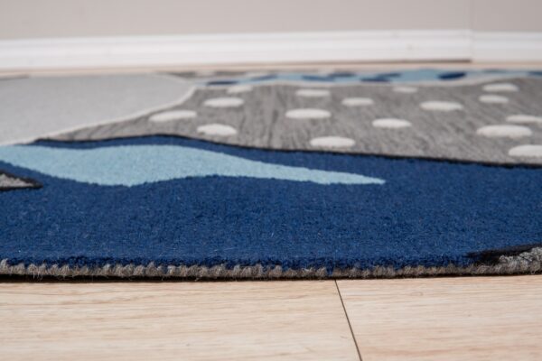 Low-pile blue and gray patterned rug with white dots rests on light wood plank flooring.