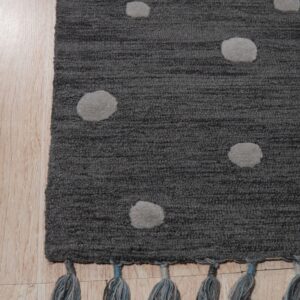 Dark gray textured rug with light gray dots and blue tassels rests on light hardwood planks.