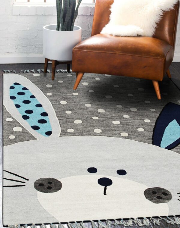 A gray bunny-shaped rug with polka dots and fringed edges rests under a brown leather chair.