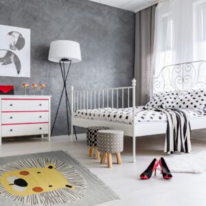 A gray rug featuring a large stylized yellow lion pattern and a white shag rug sit on light floors.