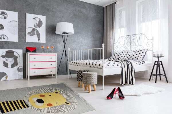 A gray rug featuring a large stylized yellow lion pattern and a white shag rug sit on light floors.