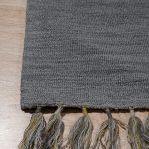 Textured gray loop-pile rug edge with gray and yellow multi-tone tassels on light wood flooring.