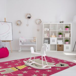 Fuchsia star and stylized cat patterned rug anchors a bright white child's room with a crib.