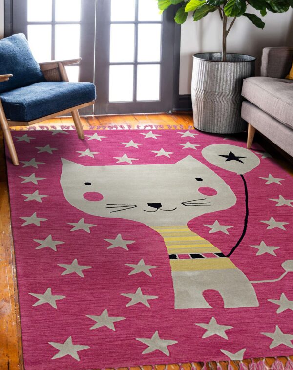 Pink rug with a graphic cat and stars on wood flooring, next to a blue chair and gray sofa.