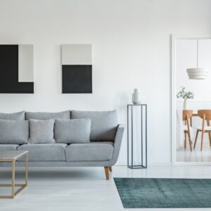 Teal textured rug with light horizontal stripes sits on white flooring in a contemporary living room.