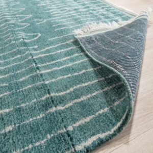 Teal and white striped high-pile rug partially rolled back on light blonde wood flooring.