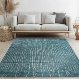 A teal rug with a white abstract striped pattern rests on light wood floors below a white sofa.