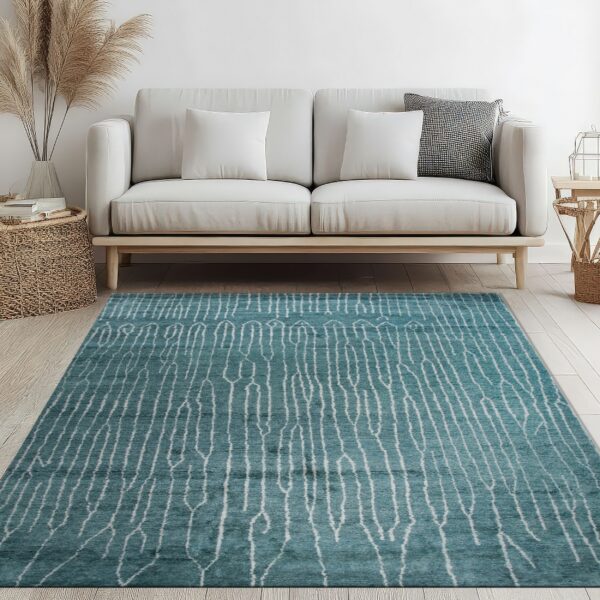 A teal rug with a white abstract striped pattern rests on light wood floors below a white sofa.