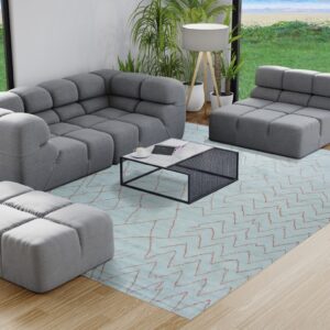 A light blue rug with reddish zigzag lines sits beneath grey modular furniture on light wood flooring.
