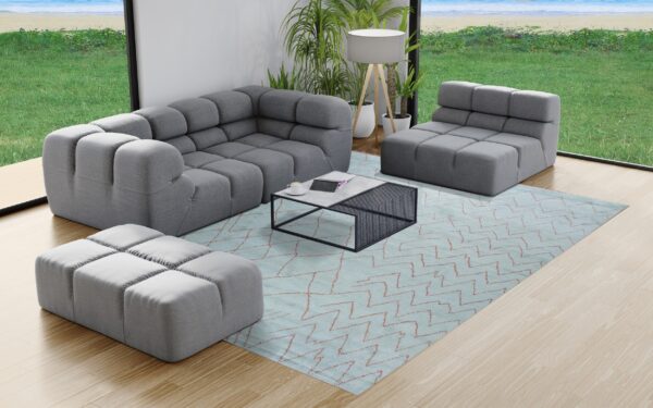 A light blue rug with reddish zigzag lines sits beneath grey modular furniture on light wood flooring.