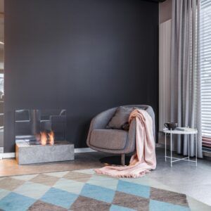 Blue and brown geometric diamond rug anchors a modern room with a gray chair and fireplace.