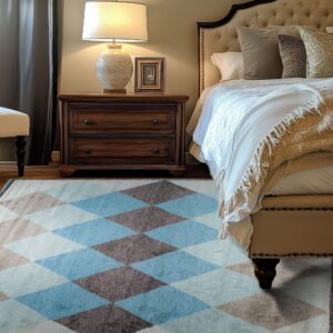 A blue, brown, and cream diamond patterned rug anchors a bedroom with dark wood flooring and plush furniture.
