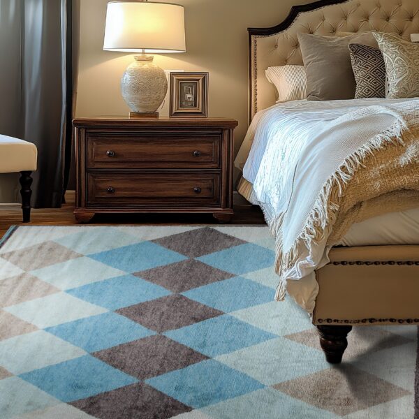 A blue, brown, and cream diamond patterned rug anchors a bedroom with dark wood flooring and plush furniture.