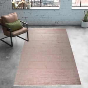 Muted pink low-pile rug on gray concrete flooring next to a leather armchair and white exposed brick wall.