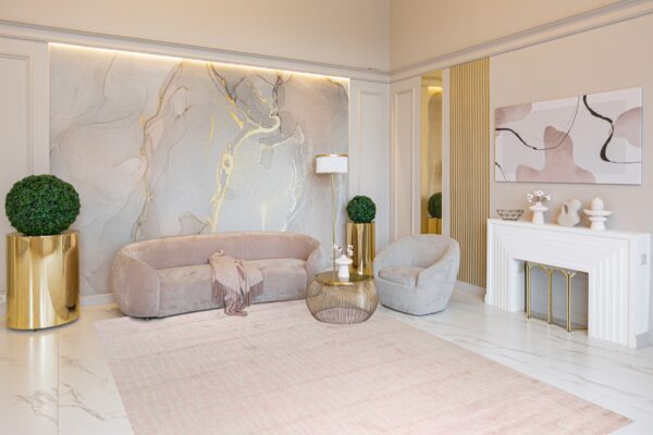 Pale pink striped area rug placed under a curved velvet sofa in a glamorous room with marble floors.