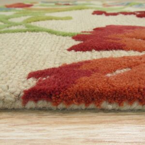 Side profile close-up of a textured rug with red, orange, and green floral designs on light wood floor.