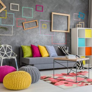 A light rug with large pink and brown floral blossoms sits under a metal coffee table in a colorful living room.