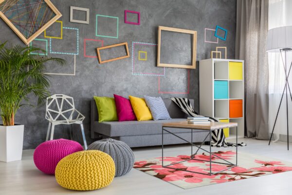 A light rug with large pink and brown floral blossoms sits under a metal coffee table in a colorful living room.