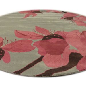 A round sage rug featuring large pink and dark brown stylized floral patterns.