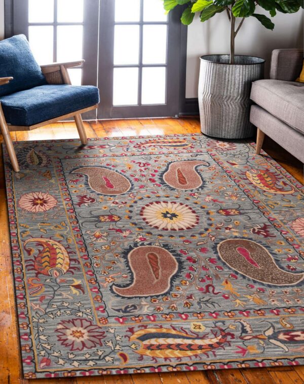 Muted blue rug with colorful paisley and floral patterns sits on wood flooring near a blue armchair.