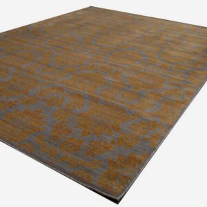 A gray area rug featuring a high-contrast distressed floral pattern in golden orange.