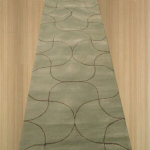 A plush sage runner rug with repeating brown ogee patterns sits on light wood flooring.