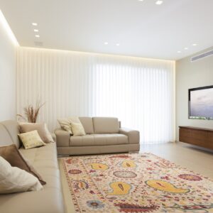 Beige rug featuring vibrant yellow paisley and multicolored floral patterns in a modern, brightly lit living space.