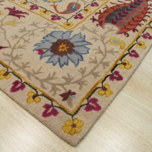 Beige rug corner with detailed blue, magenta, and orange floral patterns resting on light wood flooring.