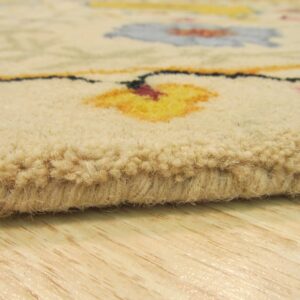 Close-up shows a thick beige rug pile with blurred yellow, pink, and blue floral motifs resting on light wooden flooring.