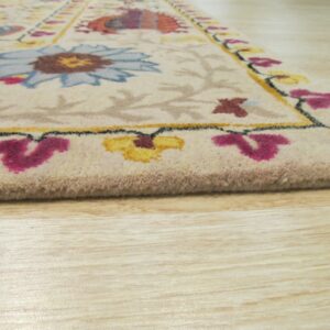 Close-up of a cream floral rug featuring blue, yellow, and magenta accents on light wood floors.