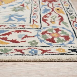 An ivory rug with red, blue, green, and yellow floral borders rests on light wood planks.