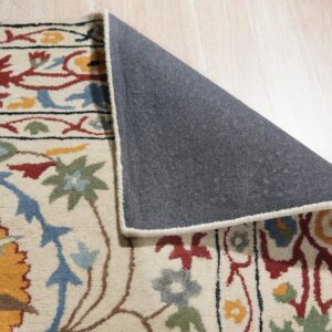 Close-up of a medium-pile, multicolored floral rug laid on light wood flooring, revealing its gray backing.