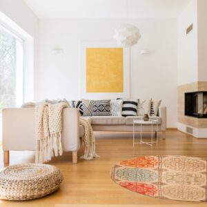 A circular rug features beige, orange, teal, and brown medallion patterns on a light wood floor.