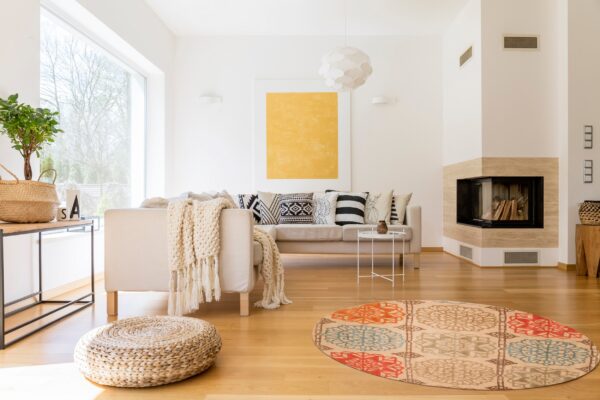 A circular rug features beige, orange, teal, and brown medallion patterns on a light wood floor.